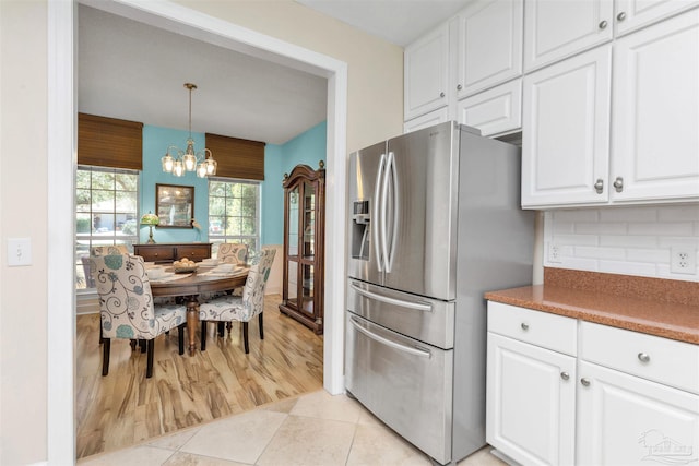 kitchen with stainless steel refrigerator with ice dispenser, backsplash, light tile patterned flooring, and white cabinets