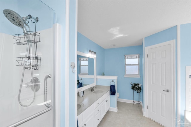 full bath featuring double vanity, visible vents, toilet, a sink, and baseboards