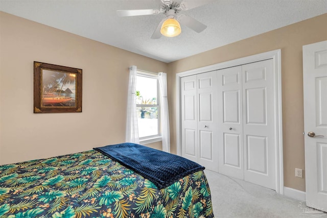 carpeted bedroom featuring a closet, ceiling fan, and a textured ceiling