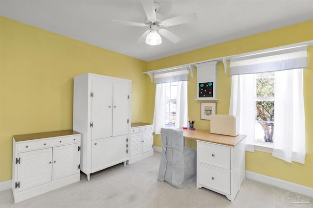 office space featuring baseboards, ceiling fan, light colored carpet, and a healthy amount of sunlight