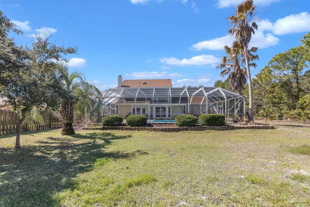 back of house with a lanai, fence, a chimney, and a lawn