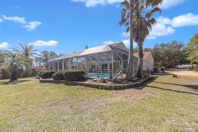 back of property featuring glass enclosure, a chimney, an outdoor pool, and a lawn