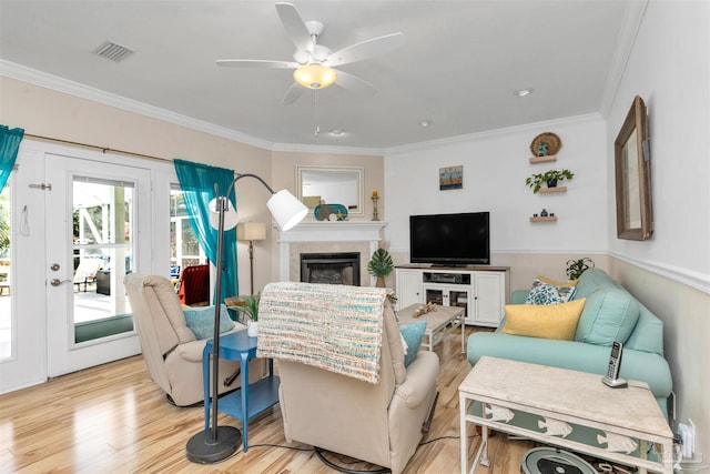 living area featuring light wood-style floors, a fireplace, crown molding, and visible vents