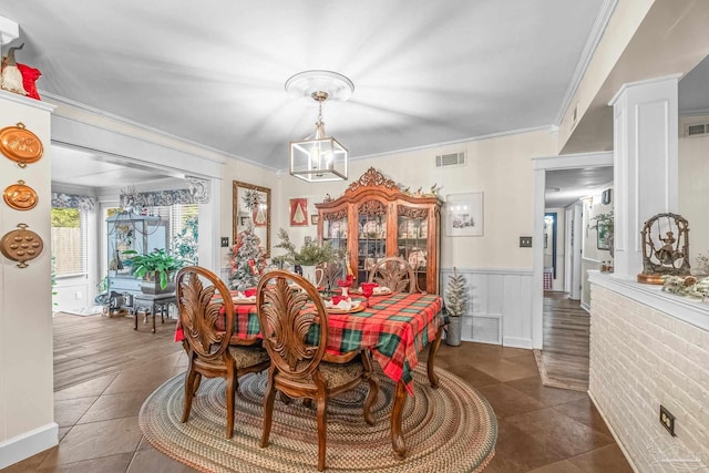 dining room with an inviting chandelier, dark tile patterned floors, and ornamental molding