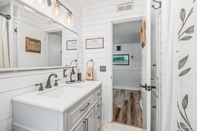 bathroom featuring hardwood / wood-style floors, vanity, and wooden walls