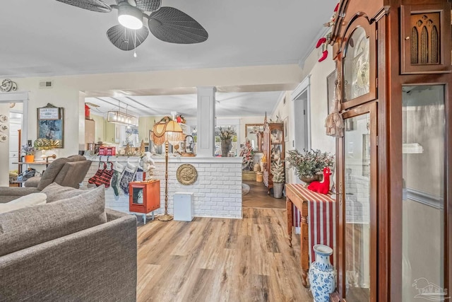 living room featuring hardwood / wood-style flooring, ceiling fan, ornate columns, and ornamental molding