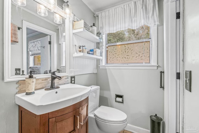 bathroom featuring vanity, a healthy amount of sunlight, toilet, and ornamental molding