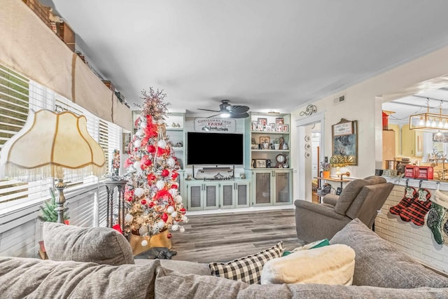 living room with ceiling fan with notable chandelier and dark hardwood / wood-style flooring