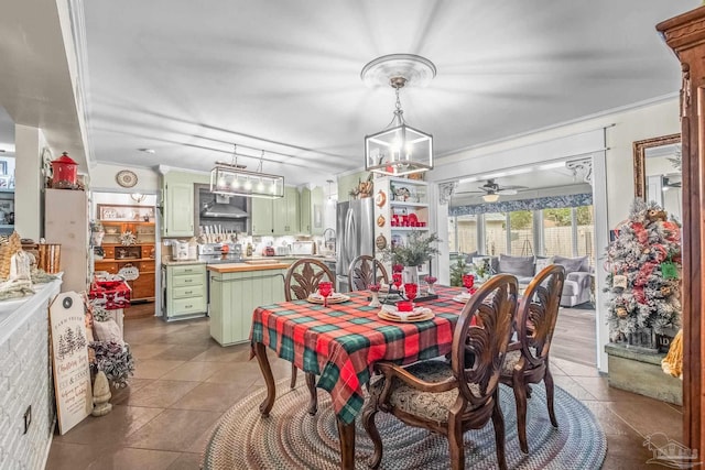 tiled dining space with ceiling fan and ornamental molding