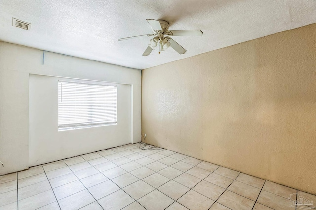 tiled empty room featuring ceiling fan and a textured ceiling