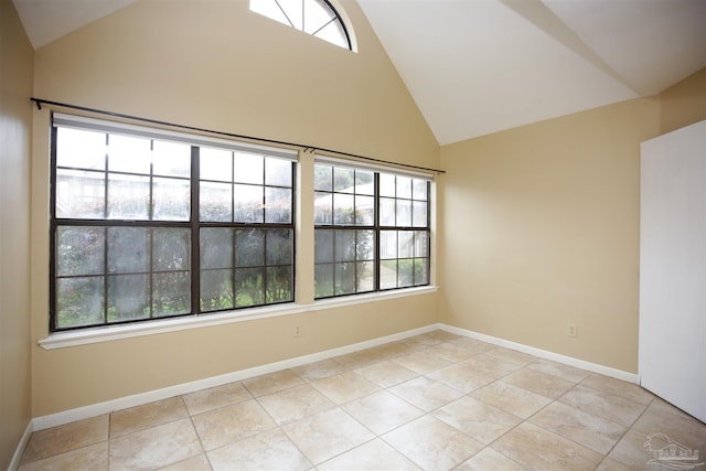 empty room with high vaulted ceiling and light tile patterned flooring