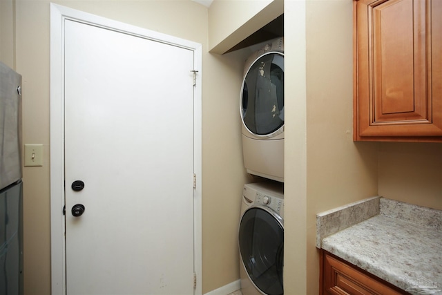 washroom with stacked washer and clothes dryer and cabinets