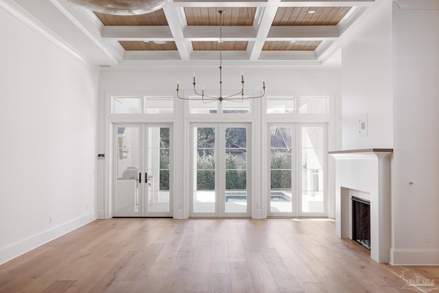 unfurnished living room with a fireplace, a notable chandelier, wood ceiling, light wood-type flooring, and baseboards