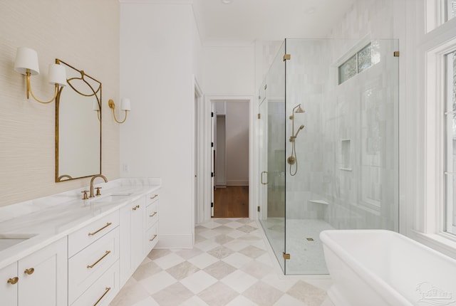 full bath with double vanity, a sink, a shower stall, a freestanding tub, and baseboards