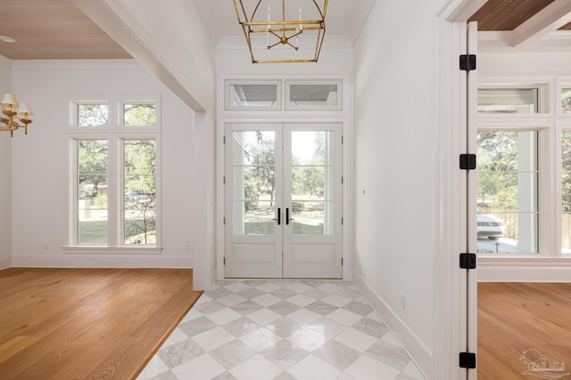 doorway to outside featuring an inviting chandelier, ornamental molding, light hardwood / wood-style flooring, and french doors