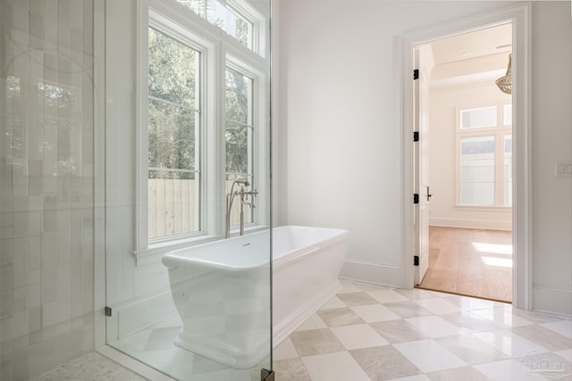 full bathroom with a healthy amount of sunlight, a freestanding tub, baseboards, and ornamental molding