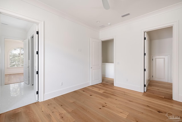 unfurnished bedroom featuring baseboards, light wood-style flooring, visible vents, and crown molding