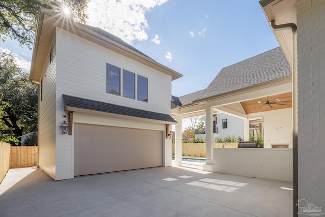 view of front of property featuring a shingled roof, an attached garage, fence, and a ceiling fan