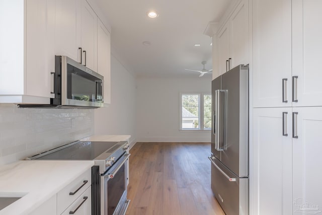 kitchen with light wood-style flooring, stainless steel appliances, white cabinets, light countertops, and tasteful backsplash