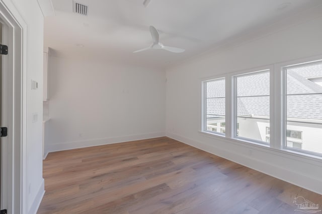 spare room featuring visible vents, a ceiling fan, ornamental molding, wood finished floors, and baseboards