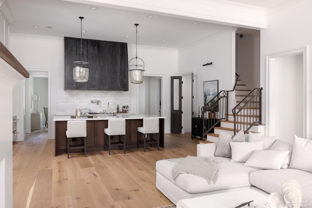 living area featuring stairs, light wood-style flooring, and crown molding