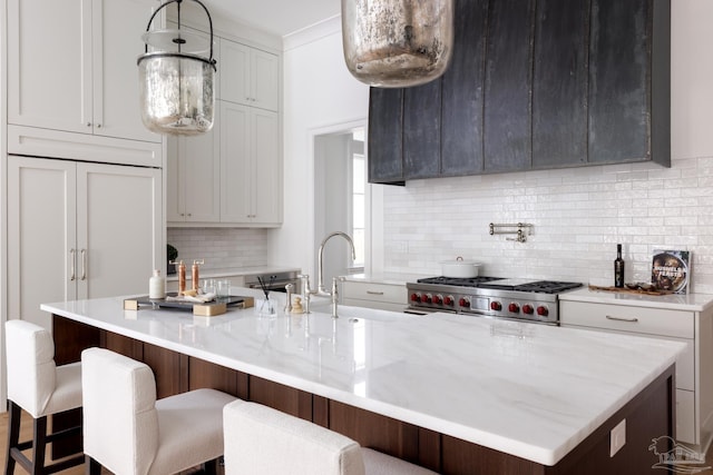 kitchen with a breakfast bar, an island with sink, and light stone counters