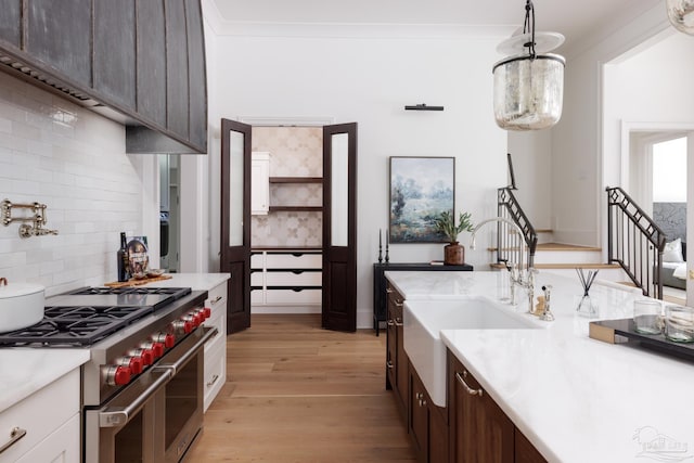 kitchen with range with two ovens, light countertops, hanging light fixtures, dark brown cabinetry, and light wood-type flooring