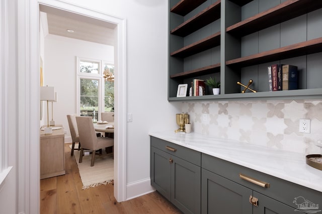 bar featuring baseboards, light wood finished floors, and tasteful backsplash