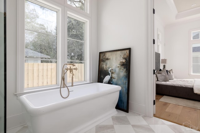 ensuite bathroom with a freestanding bath, ornamental molding, baseboards, and ensuite bathroom