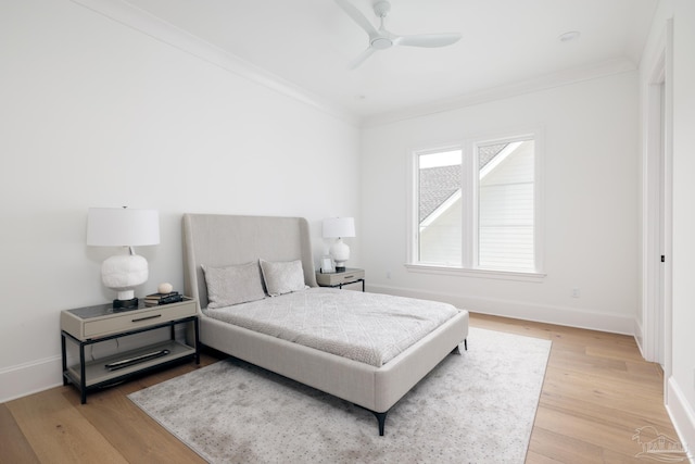 bedroom featuring light wood finished floors, ornamental molding, a ceiling fan, and baseboards