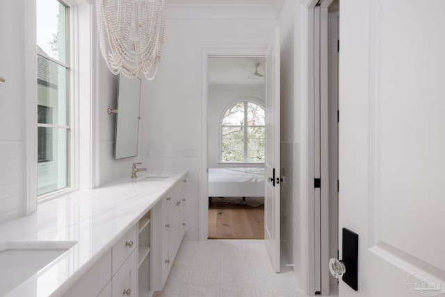 bathroom with double vanity, crown molding, a sink, and connected bathroom