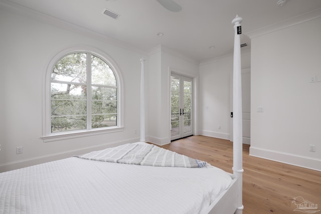 bedroom featuring light wood finished floors, baseboards, visible vents, ornamental molding, and access to exterior