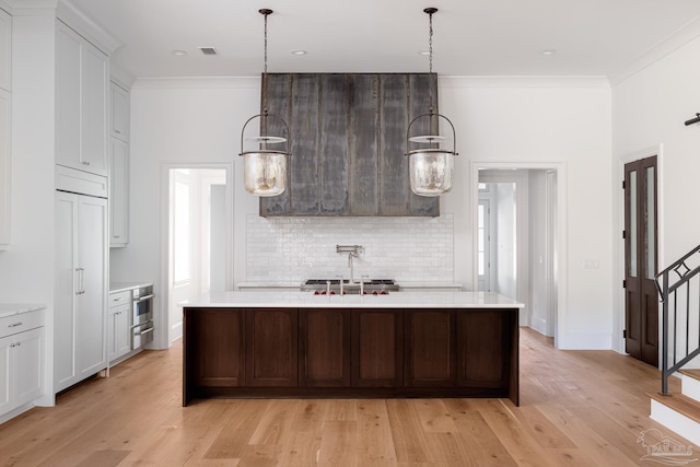 kitchen with a center island with sink, light countertops, and decorative light fixtures