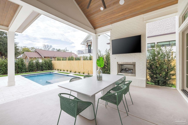 view of pool with a patio, an outdoor brick fireplace, fence, and a fenced in pool