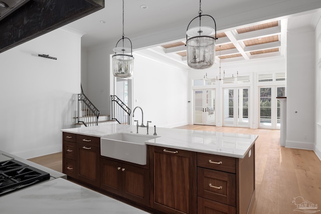 kitchen with beamed ceiling, coffered ceiling, a sink, and light wood-style floors