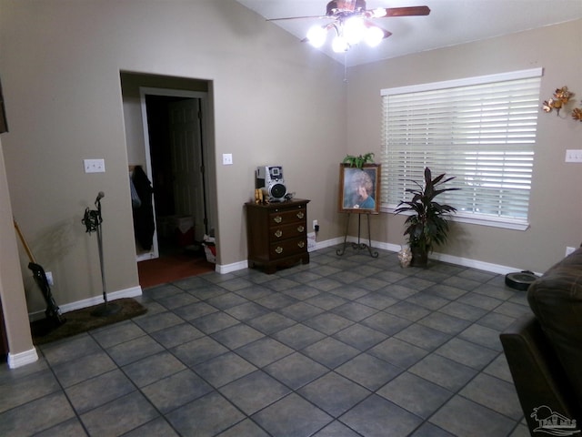 interior space with ceiling fan, dark tile patterned flooring, and lofted ceiling