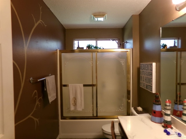 full bathroom with a textured ceiling, combined bath / shower with glass door, toilet, and vanity