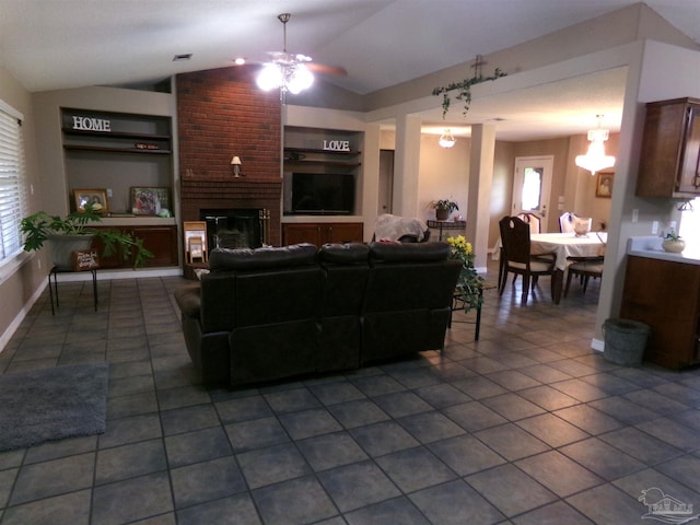 living room featuring dark tile patterned floors, built in shelves, a fireplace, vaulted ceiling, and ceiling fan