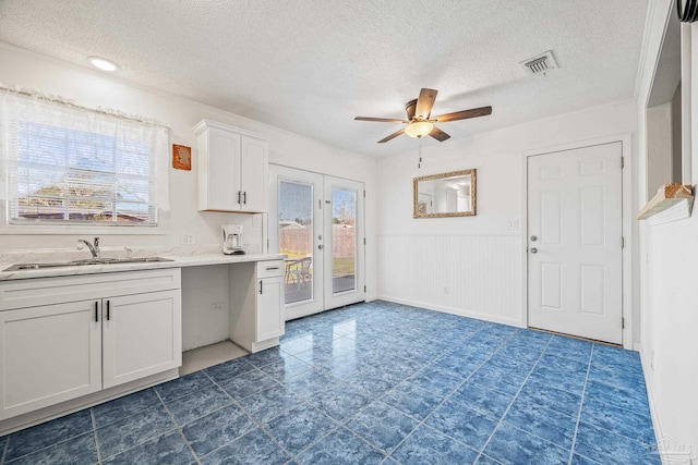 kitchen with a sink, visible vents, white cabinets, light countertops, and french doors