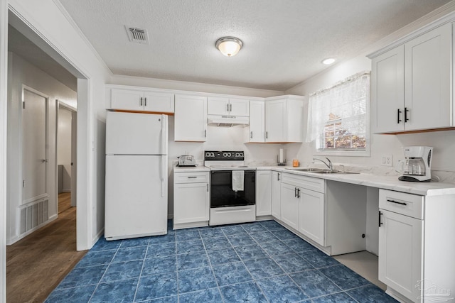 kitchen with freestanding refrigerator, visible vents, a sink, and electric range