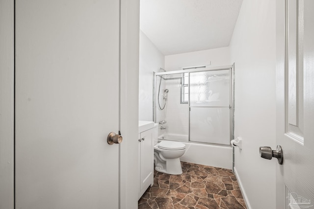 bathroom featuring stone finish flooring, enclosed tub / shower combo, baseboards, and toilet