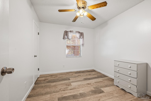 empty room featuring ceiling fan, light wood-style flooring, and baseboards