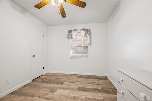 spare room with light wood-type flooring, ceiling fan, and baseboards