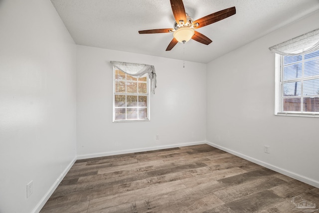 unfurnished room with ceiling fan, a textured ceiling, baseboards, and wood finished floors