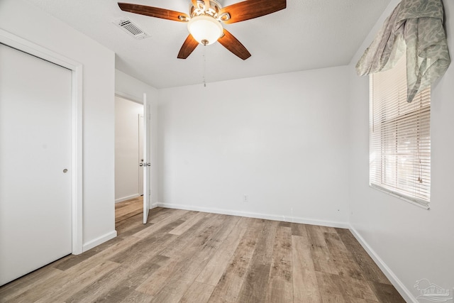 unfurnished bedroom featuring light wood finished floors, baseboards, visible vents, ceiling fan, and a closet