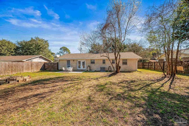 back of property with a yard, a fenced backyard, central AC, and french doors