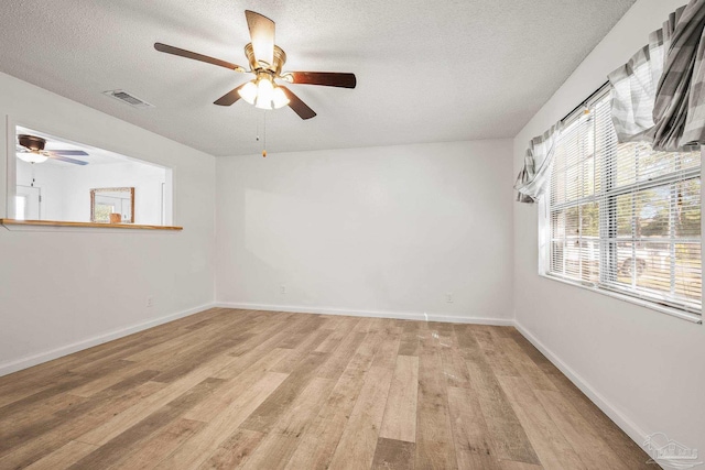 unfurnished room featuring light wood-type flooring, ceiling fan, a textured ceiling, and baseboards