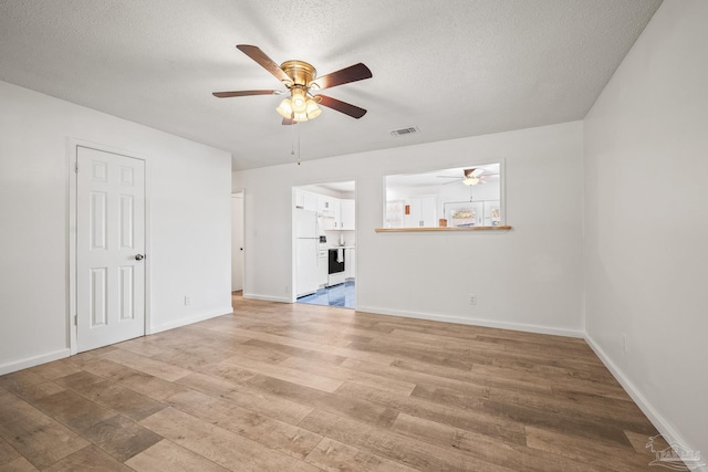 unfurnished living room featuring light wood-type flooring, baseboards, visible vents, and a textured ceiling