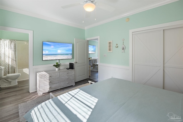 bedroom with crown molding, wood finished floors, connected bathroom, ceiling fan, and wainscoting