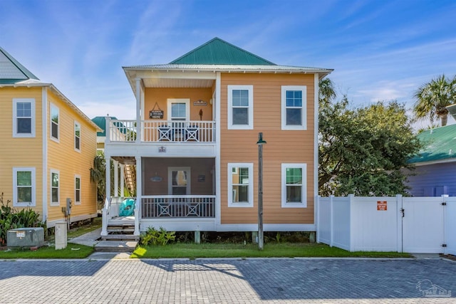 back of property featuring a balcony, fence, a porch, and central AC